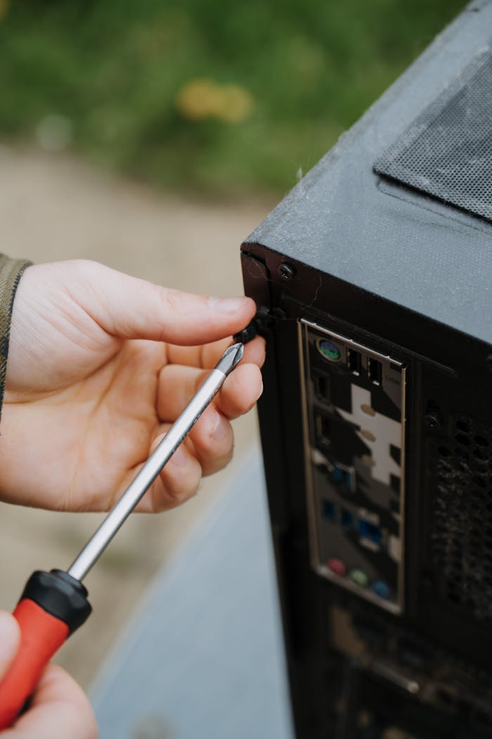 ours-journey Close-up of a person tightening screws on a PC case for maintenance.